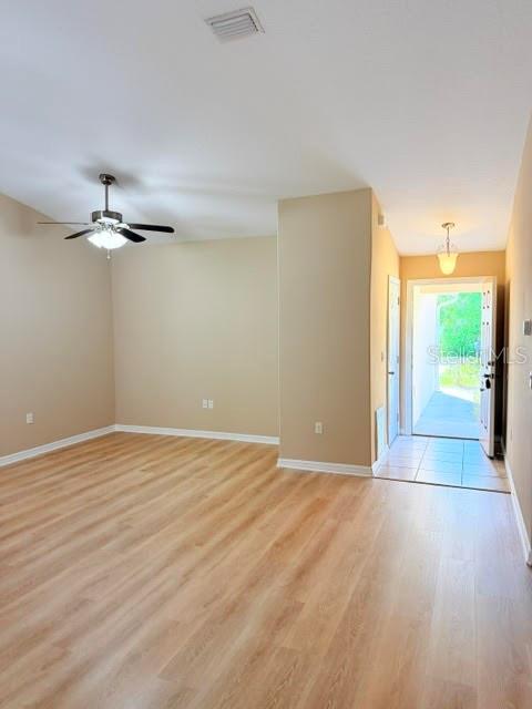 An empty room features light wood-look flooring, a ceiling fan, and an open doorway — 113 BRUNSWICK LANE UNIT A, PALM COAST, FL