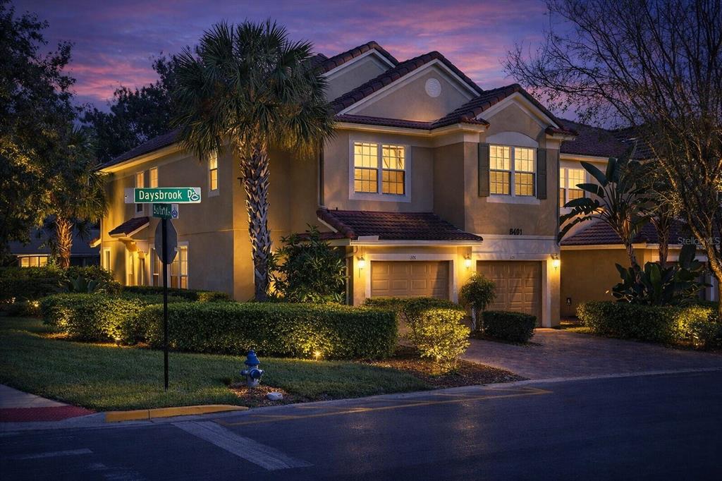 A two-story stucco townhouse with a two-car garage at dusk — 6491 DAYSBROOK DRIVE UNIT 101, ORLANDO, FL