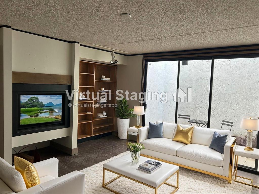 This is a virtually staged living room featuring a fireplace, built-in shelving, and sliding glass doors — 503 AVENUE B NW UNIT 503, WINTER HAVEN, FL