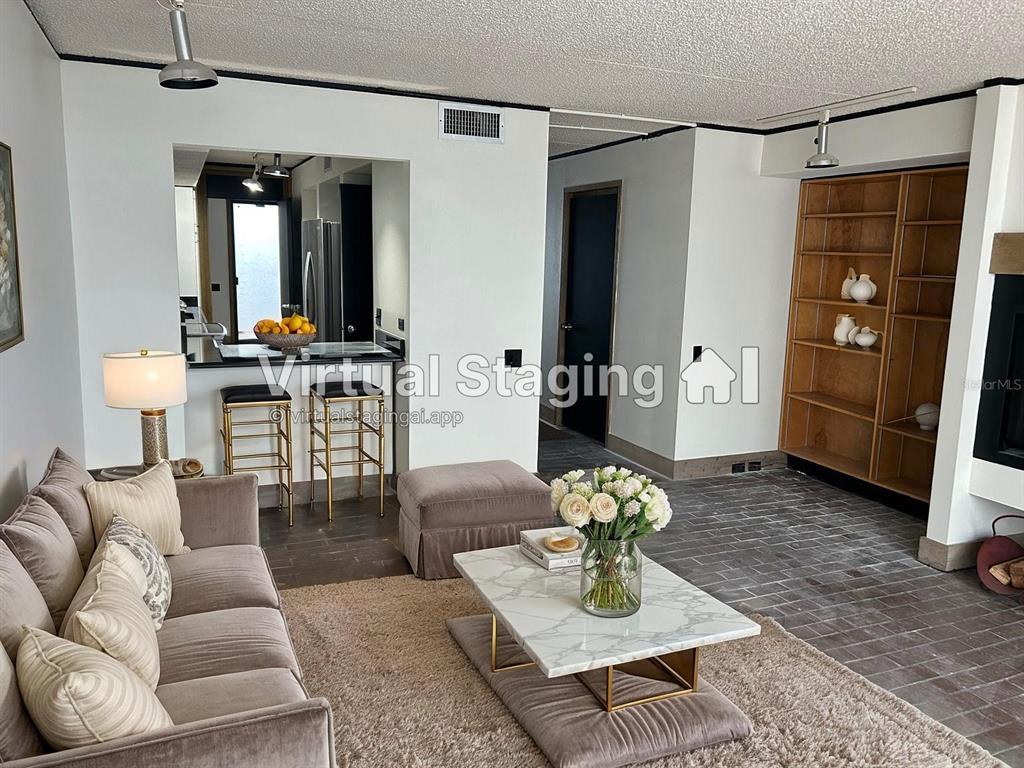 A living room with a sofa, coffee table, built-in shelving, and a kitchen breakfast bar — 503 AVENUE B NW UNIT 503, WINTER HAVEN, FL