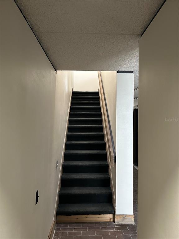 A staircase with dark carpeted steps leads upward between two plain, light-colored walls — 503 AVENUE B NW UNIT 503, WINTER HAVEN, FL