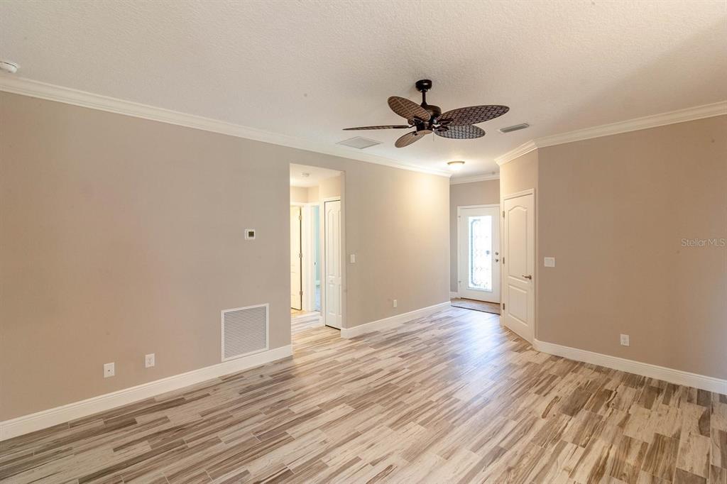 An interior view of a room with wood-look tile flooring, beige walls, and a ceiling fan — 16200 LENORD STREET, UMATILLA, FL