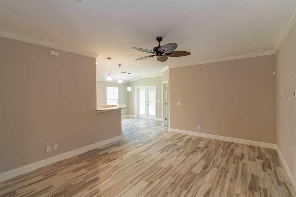 A living room with wood-look tile flooring, a ceiling fan, and an open kitchen area — 16200 LENORD STREET, UMATILLA, FL