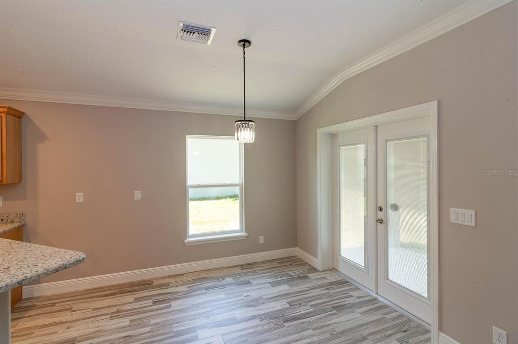 A dining area features light gray walls, wood-look tile flooring, a pendant light, and French doors — 16200 LENORD STREET, UMATILLA, FL