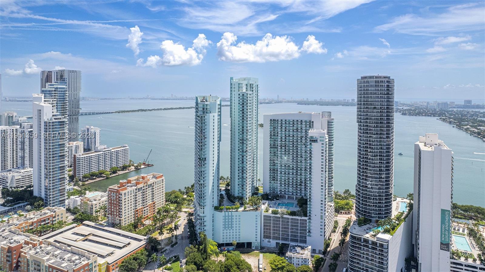 An aerial view shows multiple high-rise apartment buildings along a waterfront in a city — 1900 N BAYSHORE DR, Miami FL 33132, MIAMI, FL