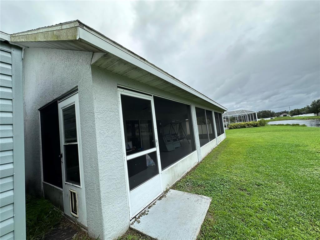 A screened-in porch with a concrete pad sits beside a house overlooking a pond — 2711 46TH STREET E, PALMETTO, FL