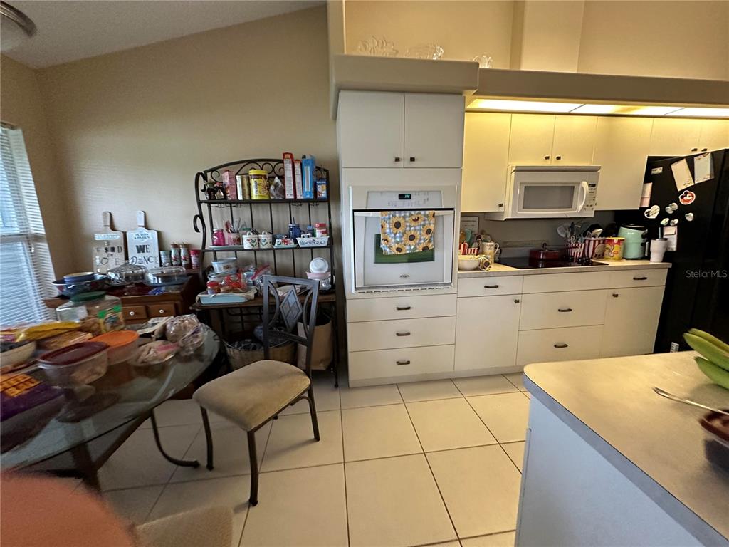 A kitchen features white cabinets, a built-in oven, a microwave, and a glass-topped dining table — 2711 46TH STREET E, PALMETTO, FL