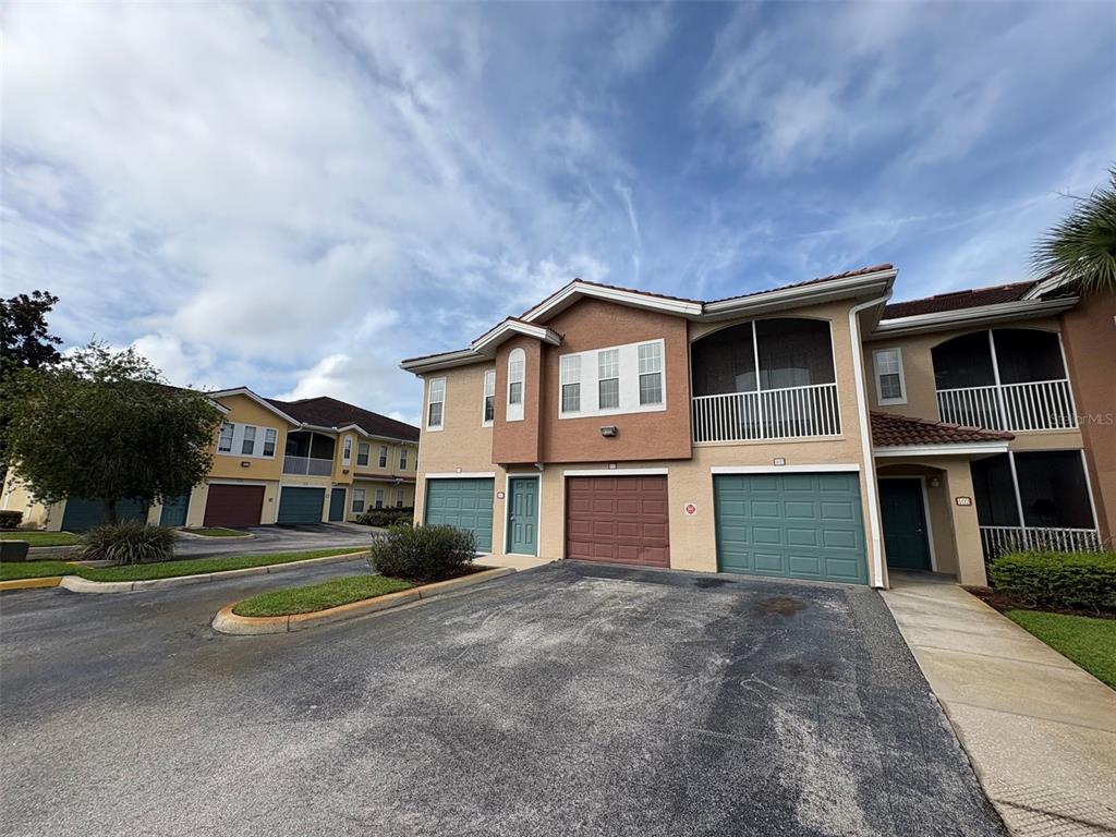 A two-story residential building with multiple garage doors and a paved driveway — 12021 VILLANOVA DRIVE UNIT 112, ORLANDO, FL