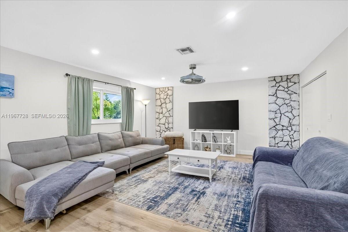 A living room features a large gray sectional, a blue sofa, and stone accent walls — 3211 Calle Largo Dr, Hollywood FL 33021, HOLLYWOOD, FL