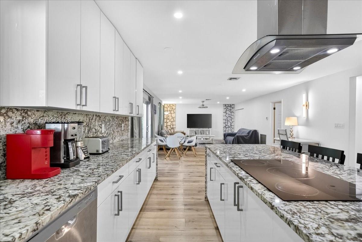 A modern kitchen with white cabinets, granite countertops, and a central island with a cooktop — 3211 Calle Largo Dr, Hollywood FL 33021, HOLLYWOOD, FL