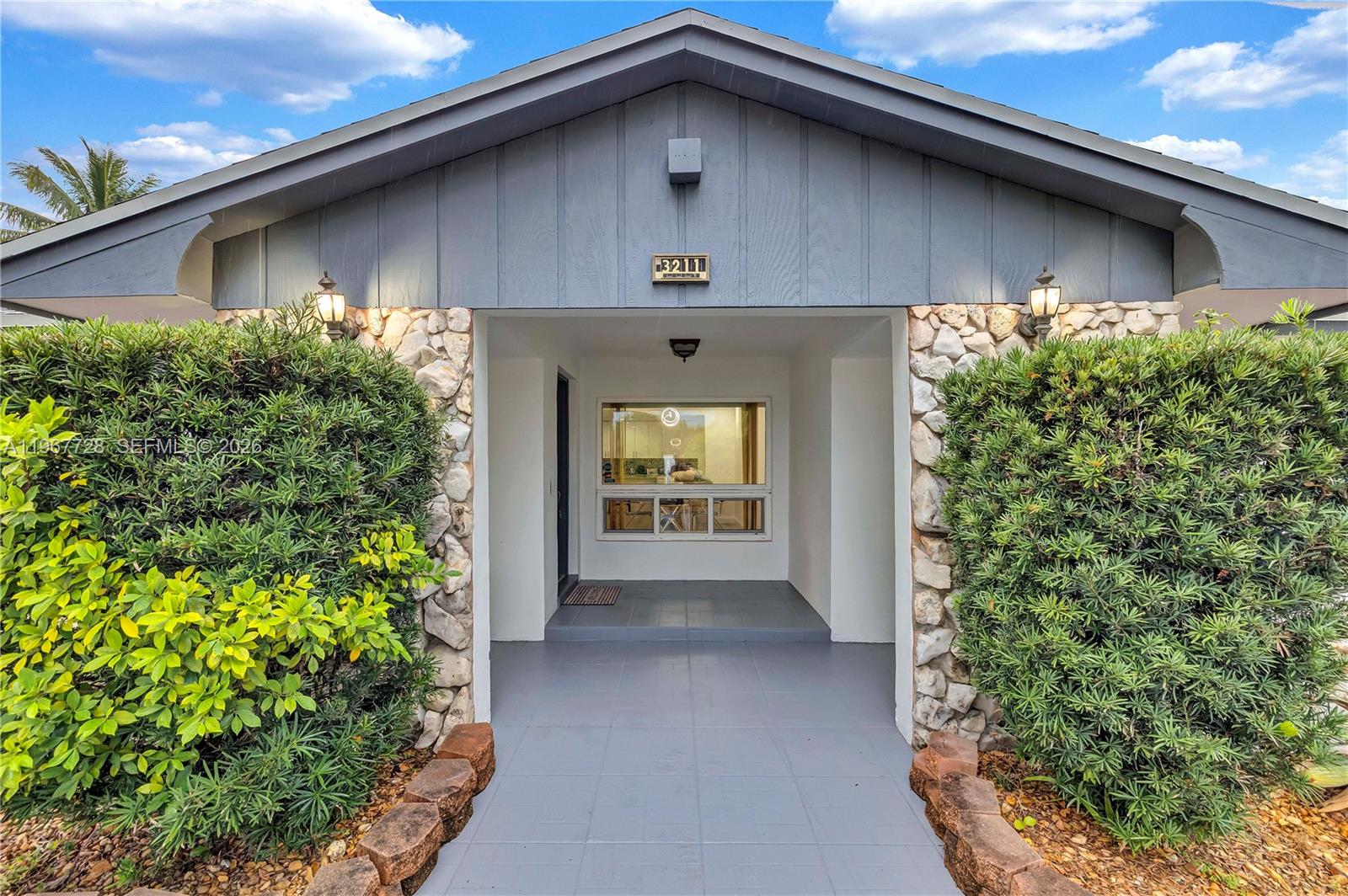 The front entrance features a tiled walkway, stone accents, and large bushes under a gable roof — 3211 Calle Largo Dr, Hollywood FL 33021, HOLLYWOOD, FL