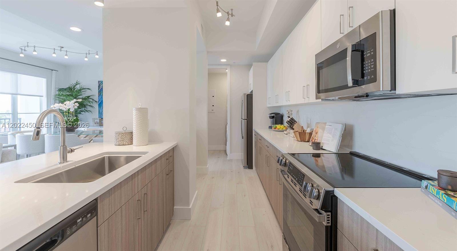 A modern kitchen features white upper cabinets, wood-toned lower cabinets, and stainless steel appliances — 151 NE 5th Ave, Delray Beach FL 33483, DELRAY BEACH, FL