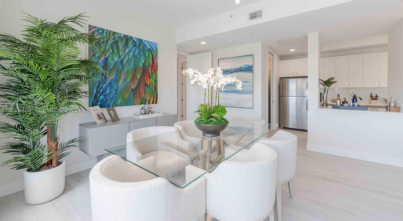 A dining room features a glass table, six white chairs, and a large potted plant — 151 NE 5th Ave, Delray Beach FL 33483, DELRAY BEACH, FL