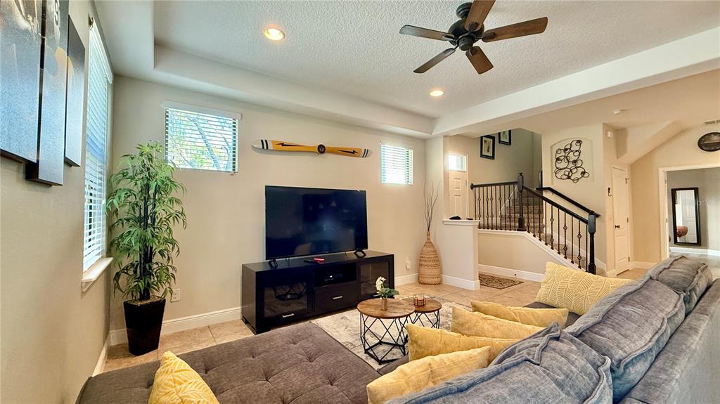 A living room features a large gray sectional sofa, a television on a stand, and stairs — 8209 ROSEVILLE ROAD, DAVENPORT, FL