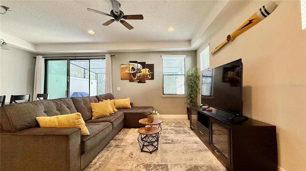 A living room features a gray sectional sofa, a television, and aviation-themed wall decor — 8209 ROSEVILLE ROAD, DAVENPORT, FL