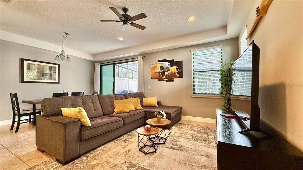 A living room features a gray sectional sofa, two round coffee tables, and a television — 8209 ROSEVILLE ROAD, DAVENPORT, FL