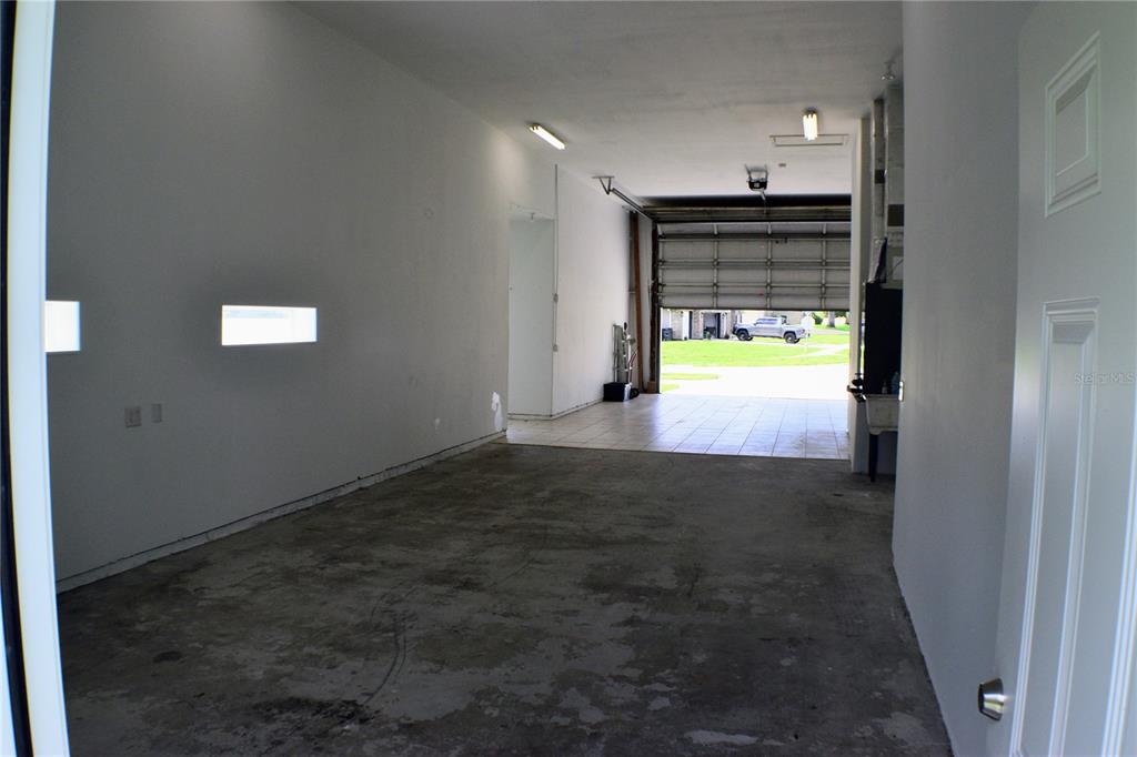 An interior view of a garage with a concrete floor and an open overhead door — 5941 MARVILLE CIRCLE, PORT ORANGE, FL