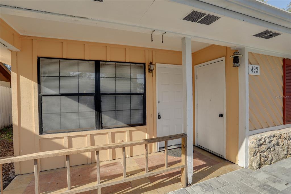 A covered porch with a wooden railing, a window, and two white entry doors — 492 TAMARACK STREET, ALTAMONTE SPRINGS, FL