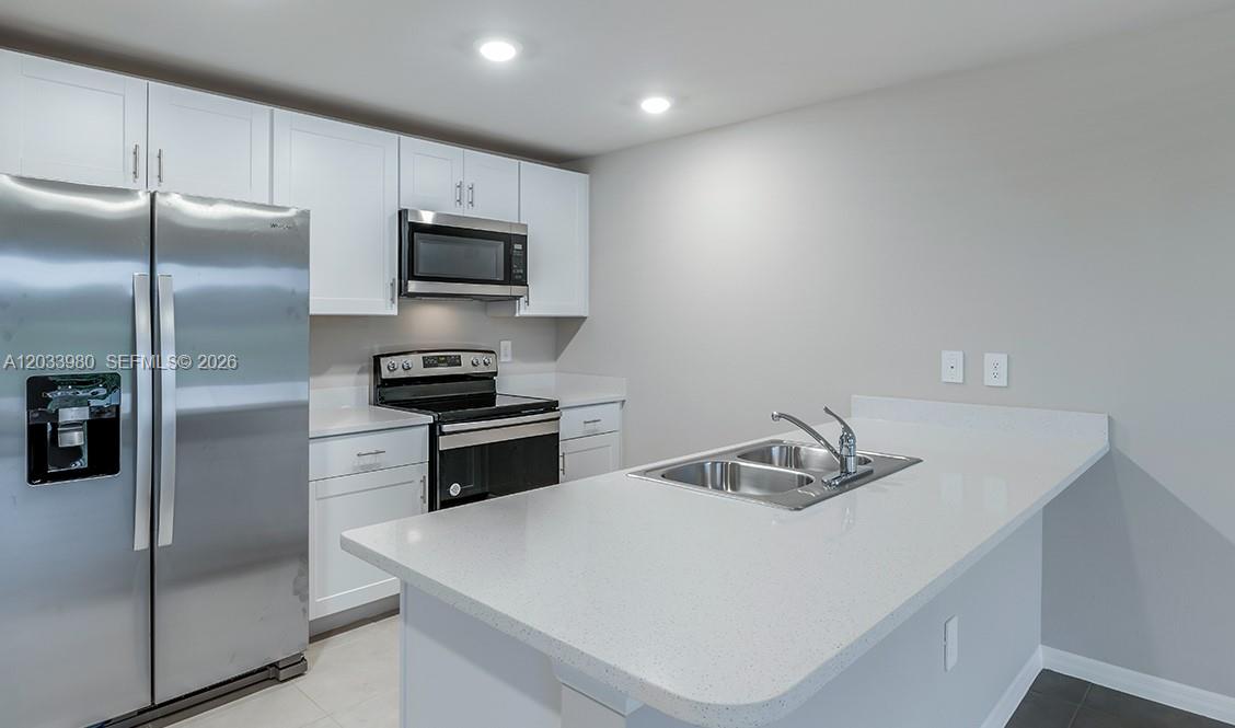A kitchen features white cabinets, stainless steel appliances, and a white quartz countertop island — 8030 OLIVE CIRCLE, La Belle FL 33935, LA BELLE, FL
