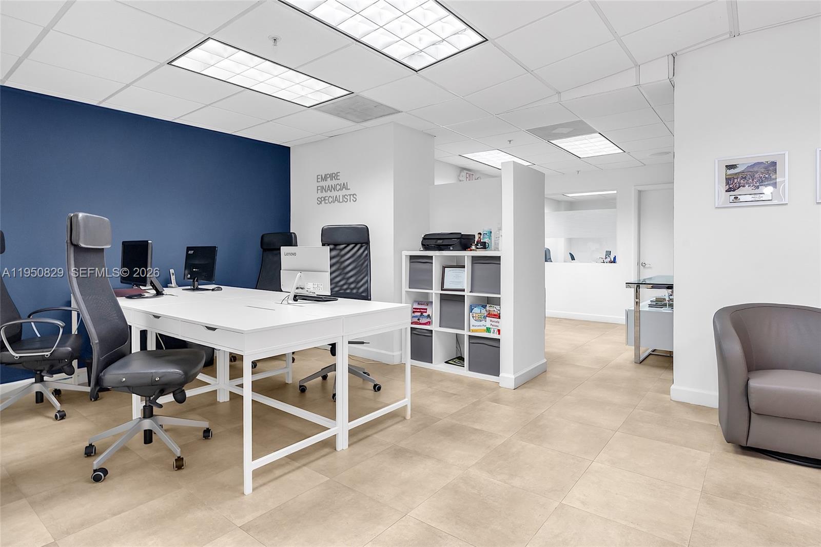 An office space features white desks, black chairs, a blue accent wall, and tiled flooring — 1110 Brickell Ave # 806, Miami FL 33131, MIAMI, FL