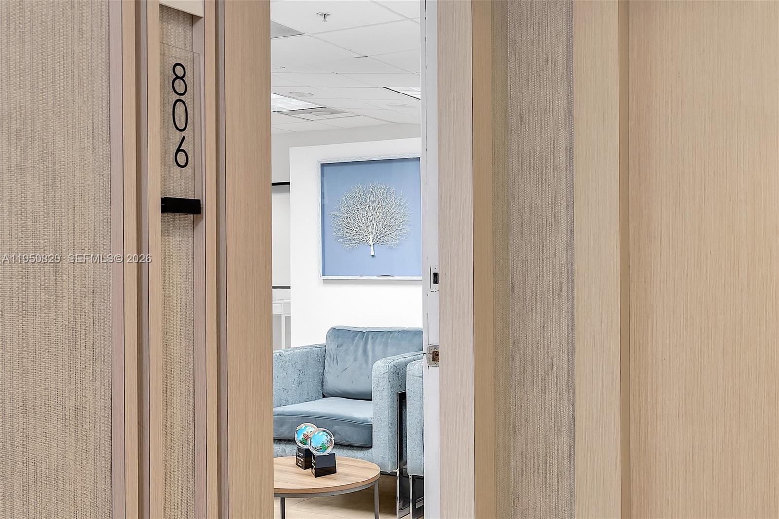 A view through a doorway into an office waiting area with a blue sofa — 1110 Brickell Ave # 806, Miami FL 33131, MIAMI, FL