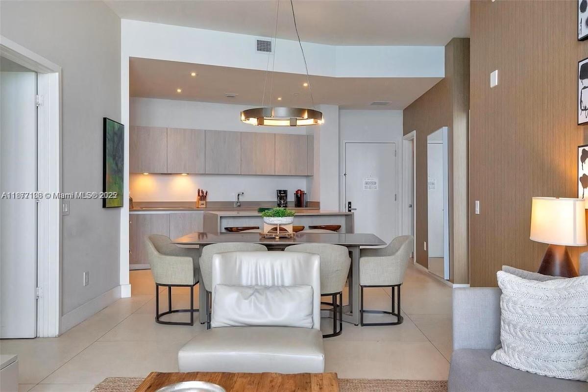 A modern open-concept kitchen and dining area features light wood cabinetry and neutral furniture — 4111 S Ocean Dr, Hollywood FL 33019, HOLLYWOOD, FL