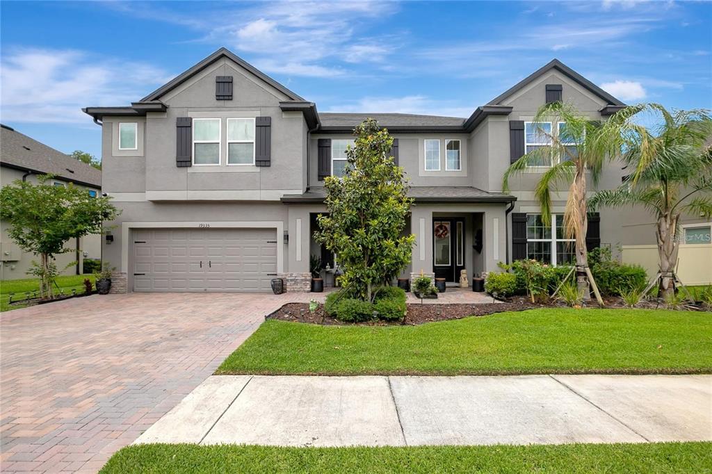 A two-story gray house with a two-car garage, brick driveway, and a front lawn — 19335 EAGLE CREEK LANE, TAMPA, FL