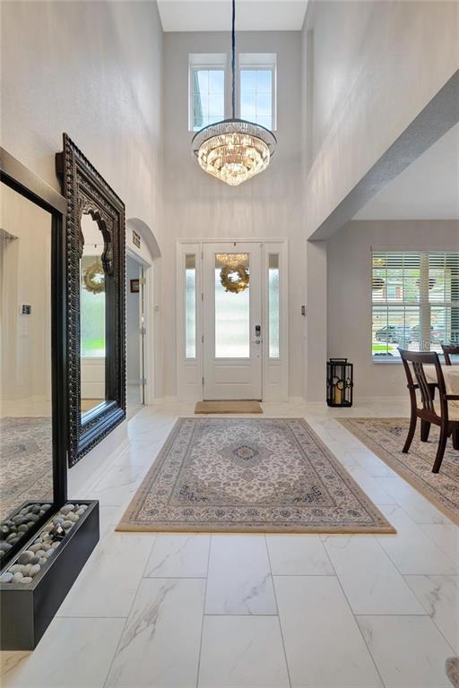 A bright foyer features white marble floors, a large ornate mirror, and a crystal chandelier — 19335 EAGLE CREEK LANE, TAMPA, FL
