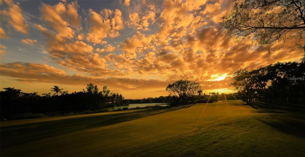 A view of a golf course fairway at sunset with trees and a lake nearby — 3527 FAIR OAKS LANE, LONGBOAT KEY, FL