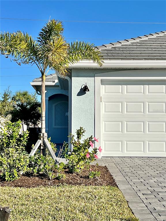 A palm tree stands in front of a house with a white garage door — 8057 SHORE LAKE DRIVE, ENGLEWOOD, FL