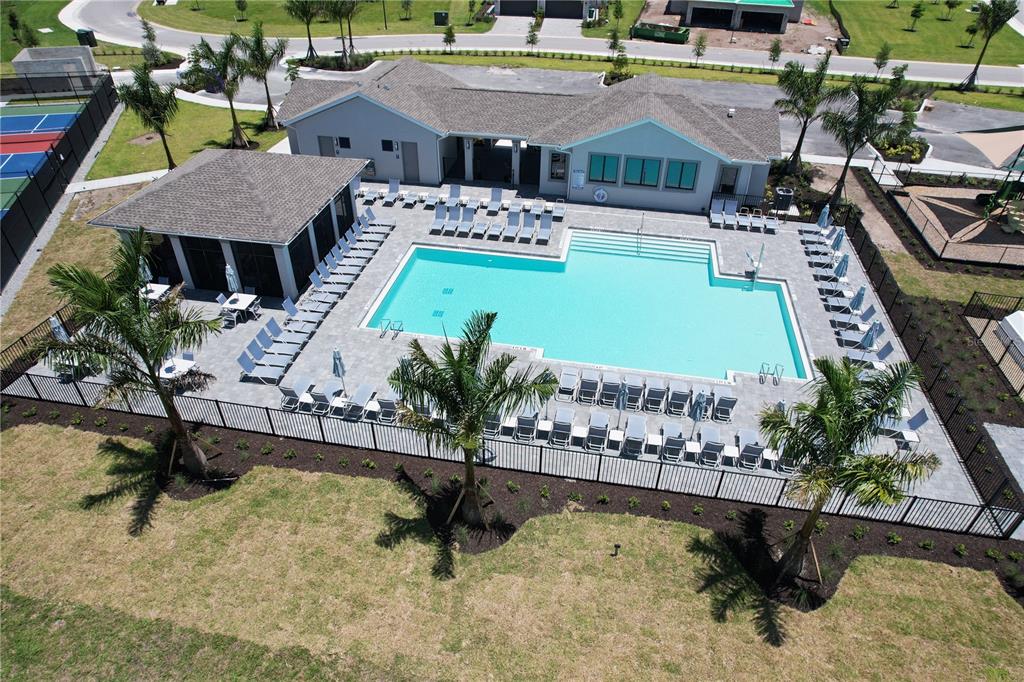 An aerial view shows a swimming pool with lounge chairs, a clubhouse, and tennis courts — 8057 SHORE LAKE DRIVE, ENGLEWOOD, FL