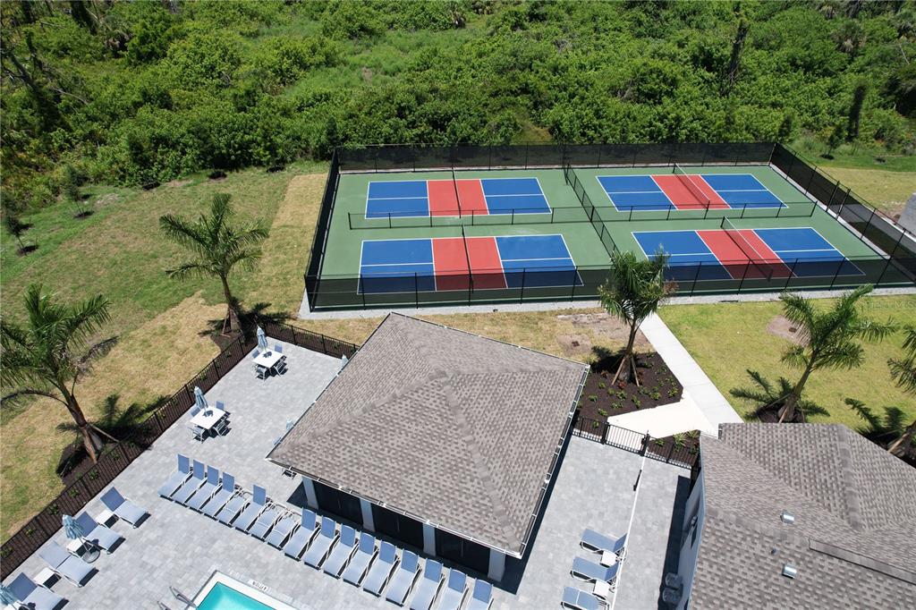 An aerial view shows a swimming pool area with lounge chairs and four pickleball courts — 8057 SHORE LAKE DRIVE, ENGLEWOOD, FL