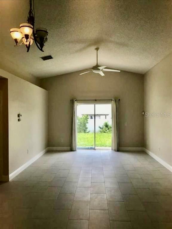 An empty room with tile flooring, a vaulted ceiling, a chandelier, and sliding glass doors — 333 PICCOLO WAY, DAVENPORT, FL