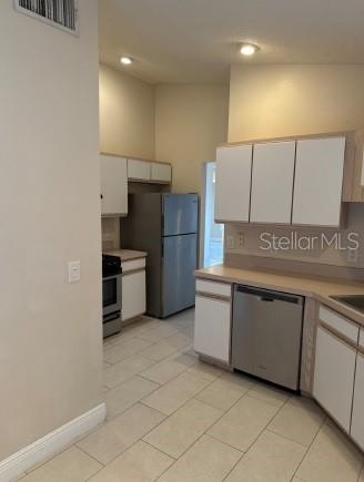 A kitchen features white cabinets, stainless steel appliances, and light-colored tile flooring — 333 PICCOLO WAY, DAVENPORT, FL