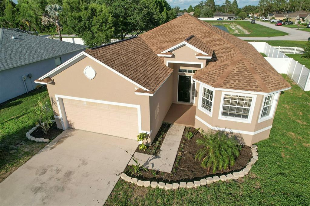 An aerial view of a single-story suburban house with a tan stucco exterior and brown roof — 5014 YELLOWTOP LOOP, LAKELAND, FL