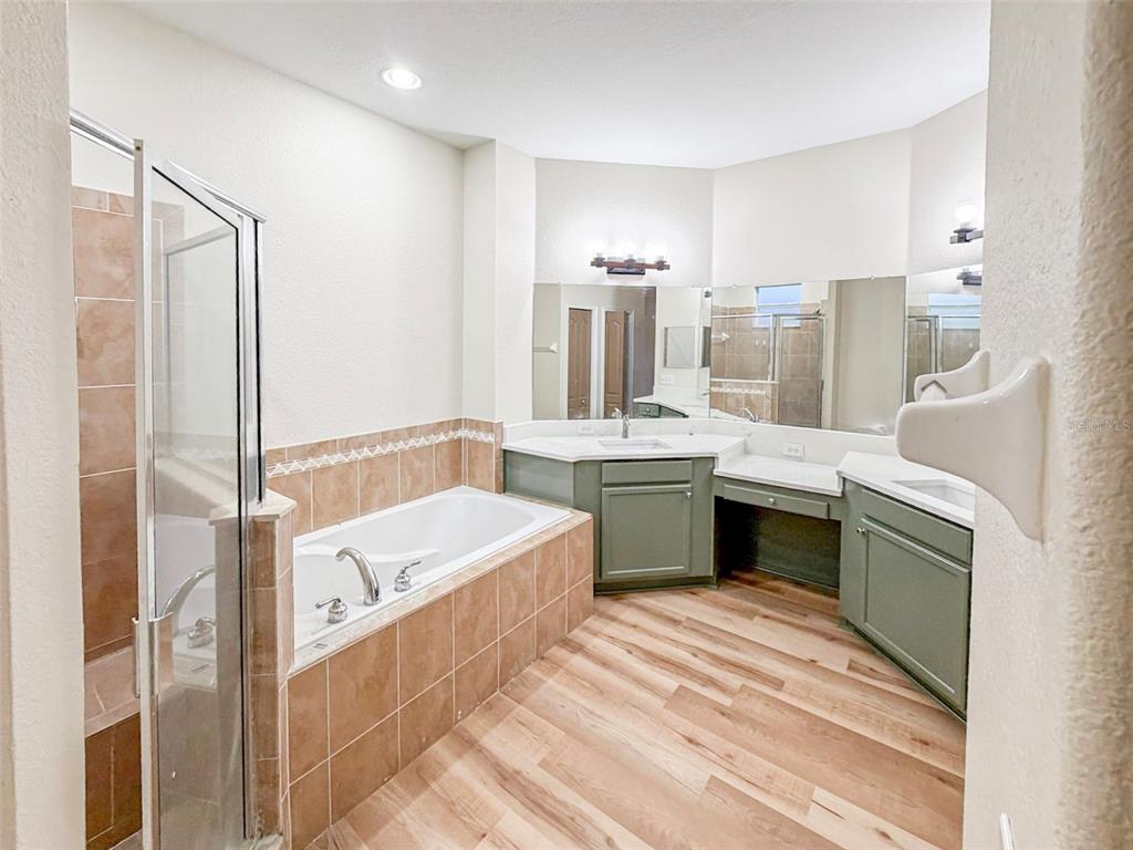 A bathroom features a tiled soaking tub, a glass shower, and green vanity cabinets — 5014 YELLOWTOP LOOP, LAKELAND, FL