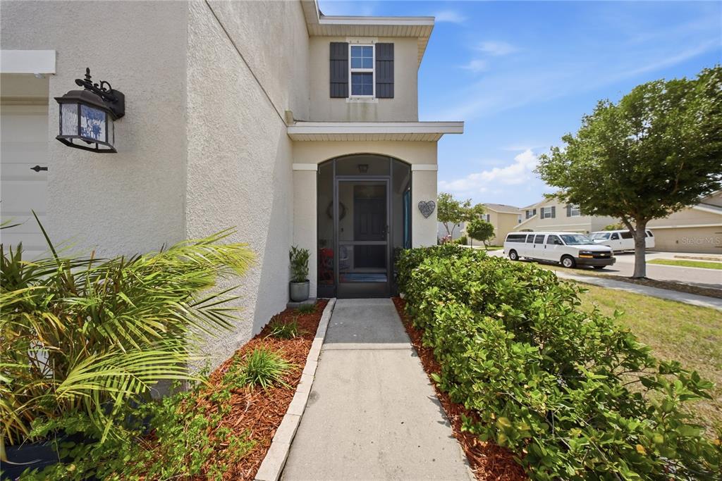 A concrete walkway leads to the screened front entrance of a two-story stucco home — 10101 MANGROVE WELL ROAD, RUSKIN, FL