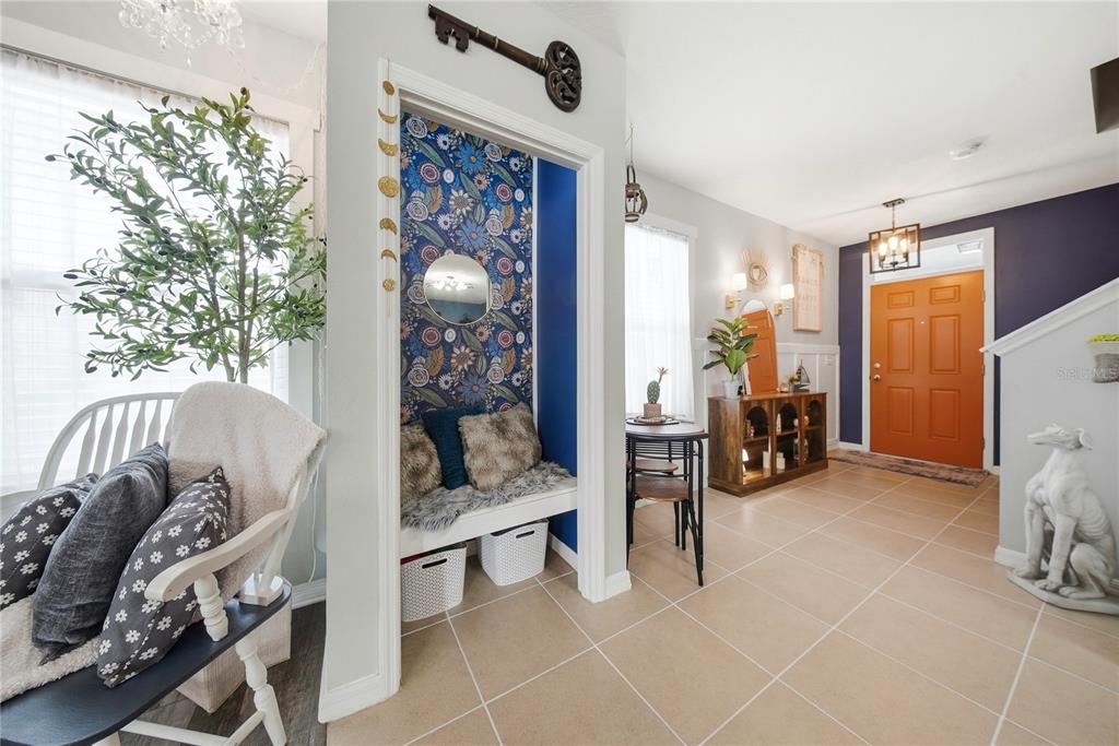 An entryway features a built-in bench with floral wallpaper, an orange door, and tile flooring — 10101 MANGROVE WELL ROAD, RUSKIN, FL