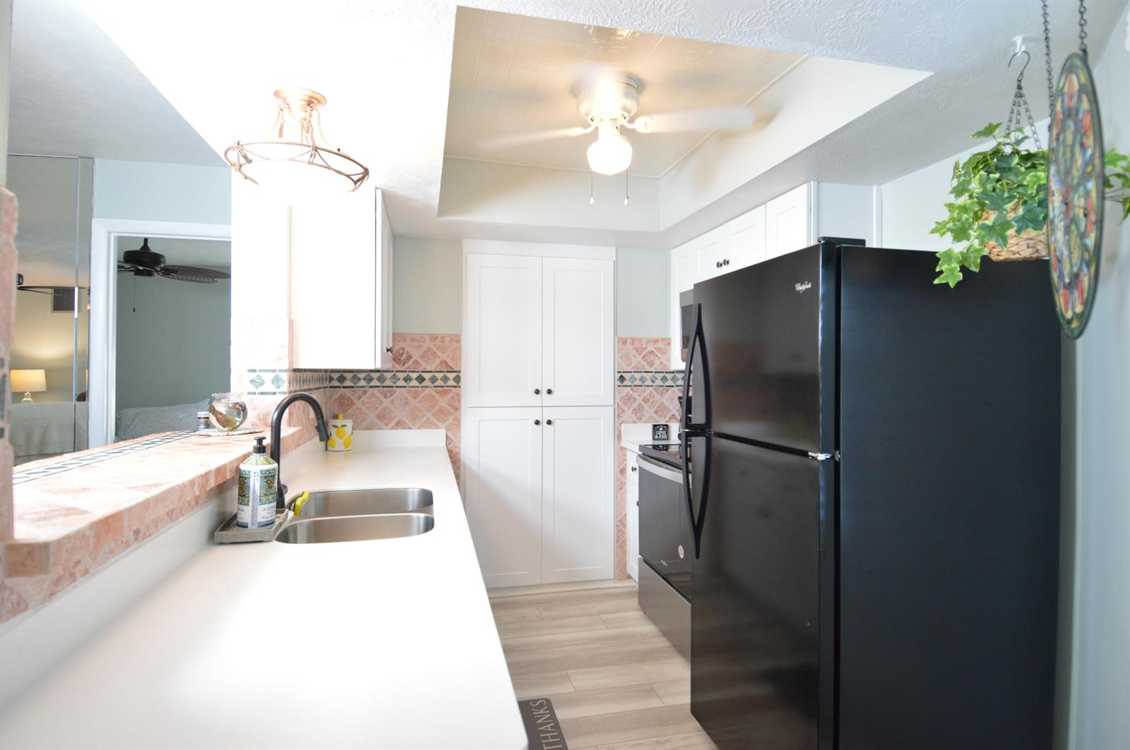 A kitchen features white cabinets, a black refrigerator, a double sink, and pink tile backsplash — 3272 SE Aster Lane # G249, Stuart FL 34994, STUART, FL