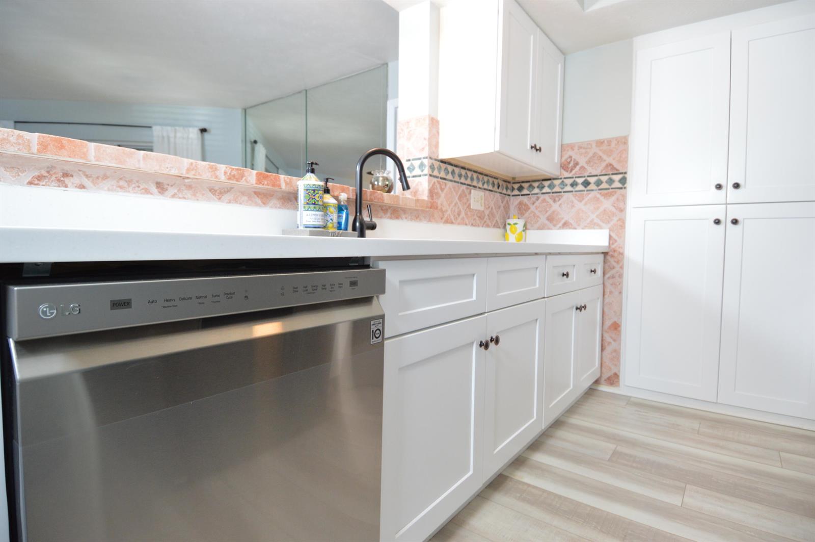 A kitchen features white cabinets, a stainless steel dishwasher, and a tiled backsplash — 3272 SE Aster Lane # G249, Stuart FL 34994, STUART, FL