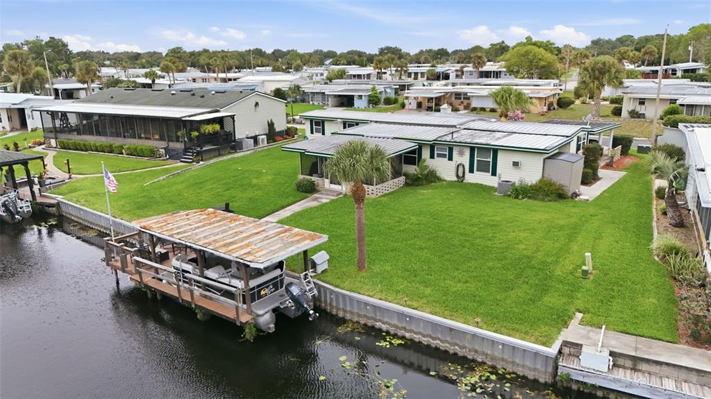 An aerial view shows a waterfront mobile home with a boat dock and grassy yard — 928 MORNINGVIEW DRIVE, TAVARES, FL