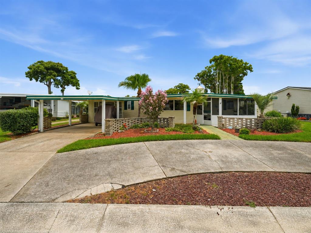 A single-story mobile home features a carport, a low brick wall, and a screened porch — 928 MORNINGVIEW DRIVE, TAVARES, FL