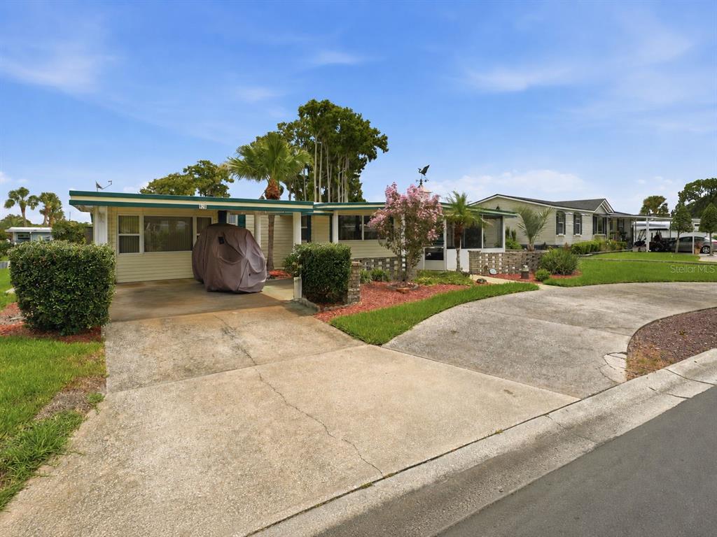 A single-story mobile home with a carport, concrete driveway, and landscaped front yard — 928 MORNINGVIEW DRIVE, TAVARES, FL