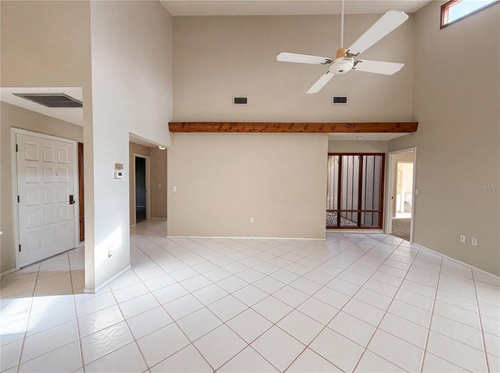 A spacious living room features white tile flooring, a vaulted ceiling with a fan, and a beam — 1407 WILLOW OAK CIRCLE UNIT 1407, BRADENTON, FL