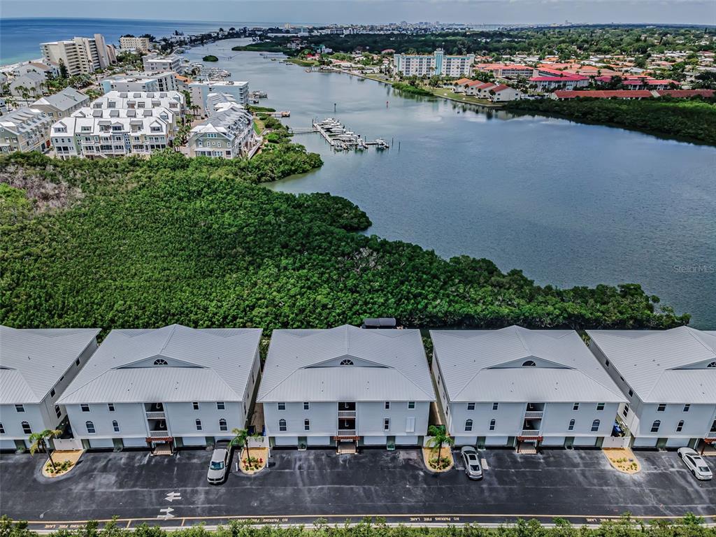 An aerial view shows a row of white townhouses with metal roofs facing a waterway — 19829 GULF BOULEVARD UNIT 501, INDIAN SHORES, FL