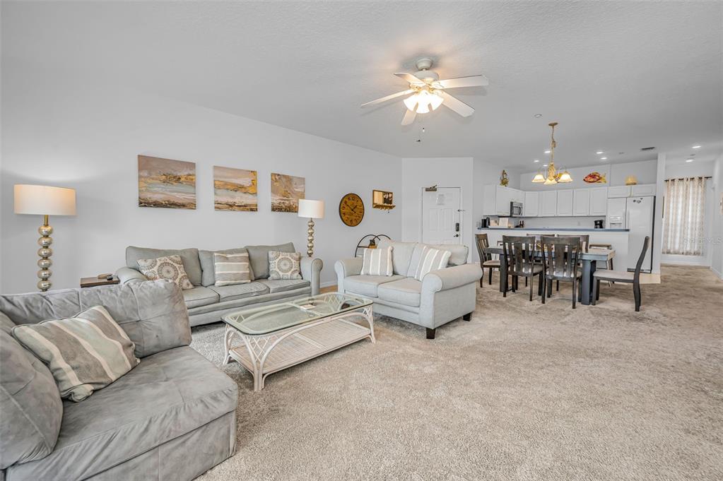 A living room with gray sofas, a glass coffee table, and an open kitchen area — 19829 GULF BOULEVARD UNIT 501, INDIAN SHORES, FL