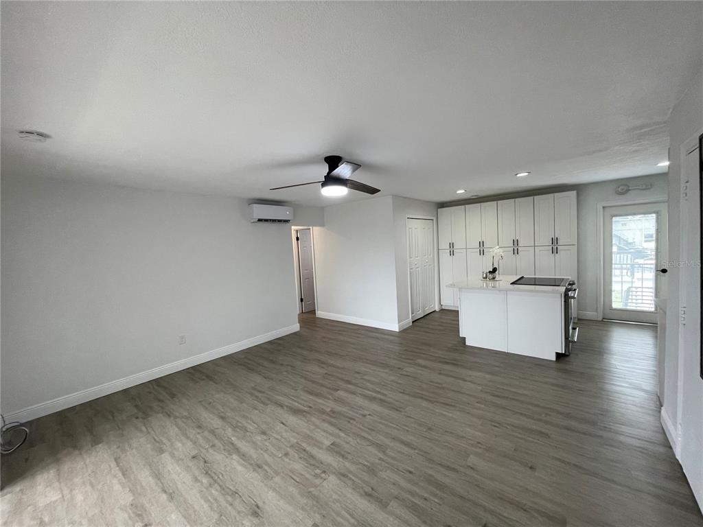 A living room with wood-look flooring, a ceiling fan, and an open kitchen island — 151 N ORLANDO AVENUE UNIT 238, WINTER PARK, FL