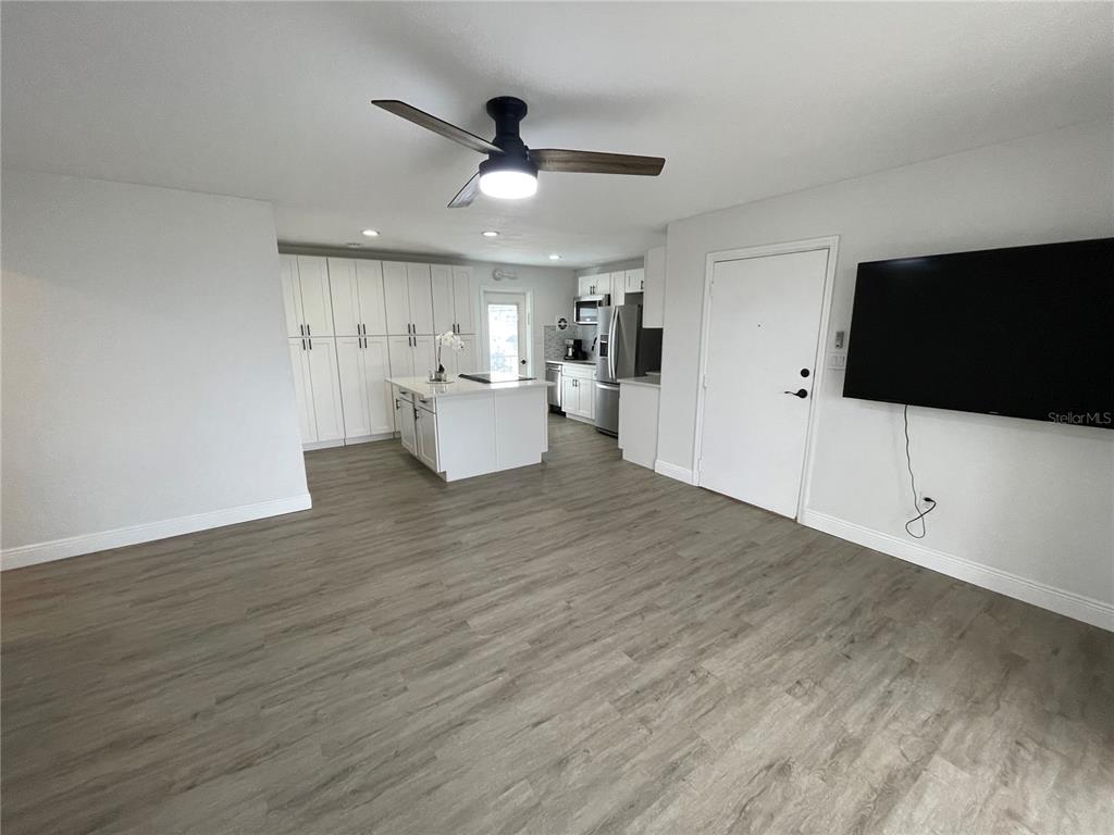 A kitchen with white cabinetry and an island opens into a living area with flooring — 151 N ORLANDO AVENUE UNIT 238, WINTER PARK, FL
