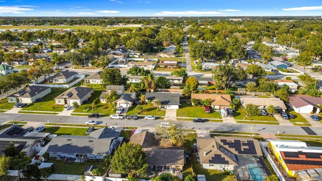 An aerial view shows a suburban neighborhood with single-family homes, green lawns, and paved streets — 1905 HUGHEY STREET, KISSIMMEE, FL
