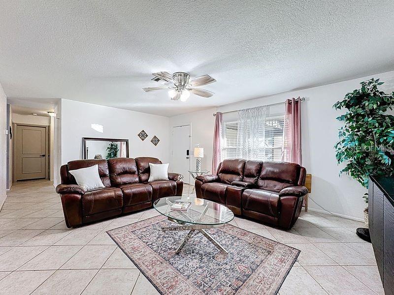 A living room features brown leather sofas, a glass coffee table, and tile flooring — 1905 HUGHEY STREET, KISSIMMEE, FL